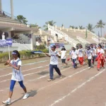 Děti soutěžící v zábavných disciplínách na zahradě školky